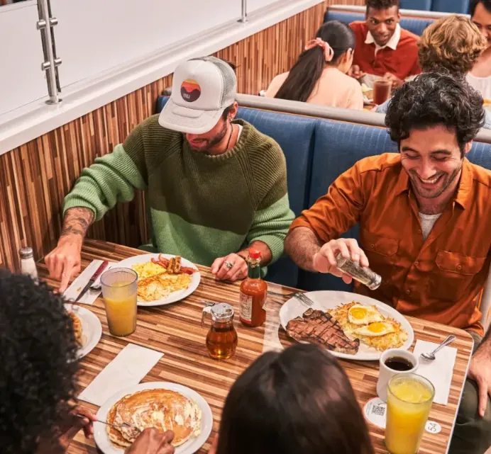 Diverse group of people enjoying delicious food at a NORMS Restaurant